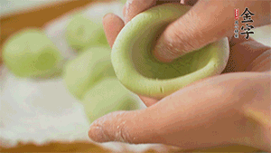 將均分的艾草面團搓成圓，挖一個窩，放入餡心，再搓成圓。