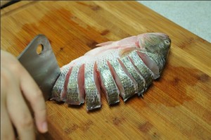 將鱸魚清洗干凈，從脊椎處切斷至腹部，腹部保留1cm左右不要切斷。