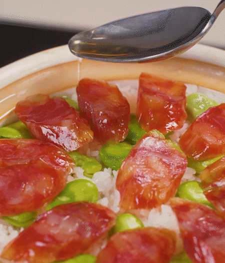 大米出現(xiàn)小孔時(shí)開蓋放香腸，往鍋邊淋入少許油，再燜煮8~10分鐘左右。