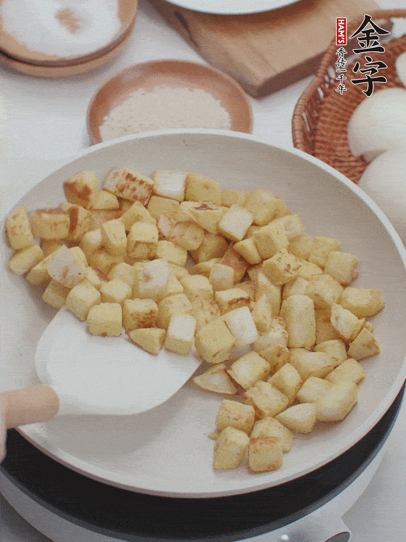 起鍋熱油，倒入饅頭丁，小火煎至蛋液凝固定型再翻面，饅頭丁部煎至金黃時(shí)盛起待用。