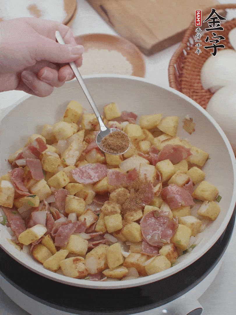 起鍋少油，煸香洋蔥丁、蔥白，加入金字培根火腿翻炒幾下，再加入饅頭丁、1小勺孜然粉、少許鹽翻炒均勻并鋪平。