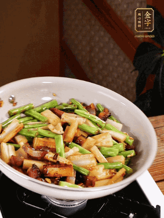 油熱下蒜末、干辣椒、醬肉煸炒出香味，依次下藕條、豆角翻炒均勻